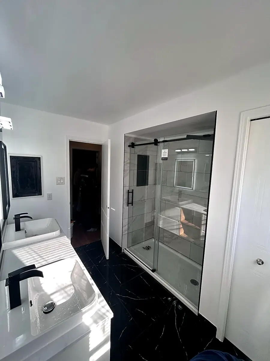 Glass shower beside double vessel sinks by Ottawa Home Reno Co.